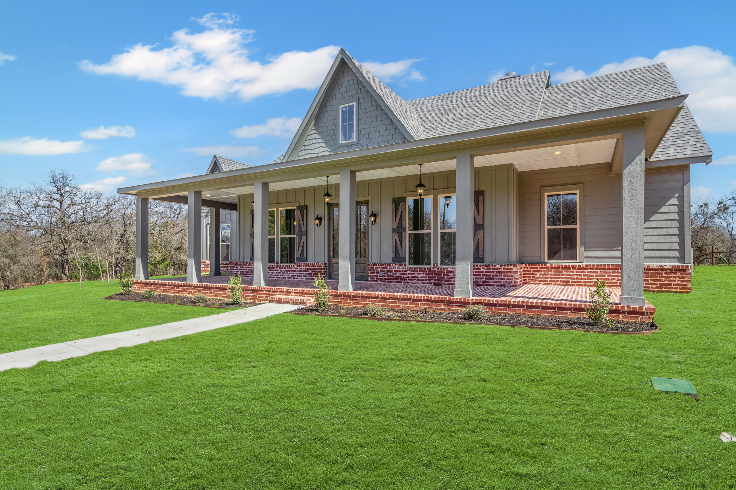 Modern farmhouse with spacious porch and green lawn.