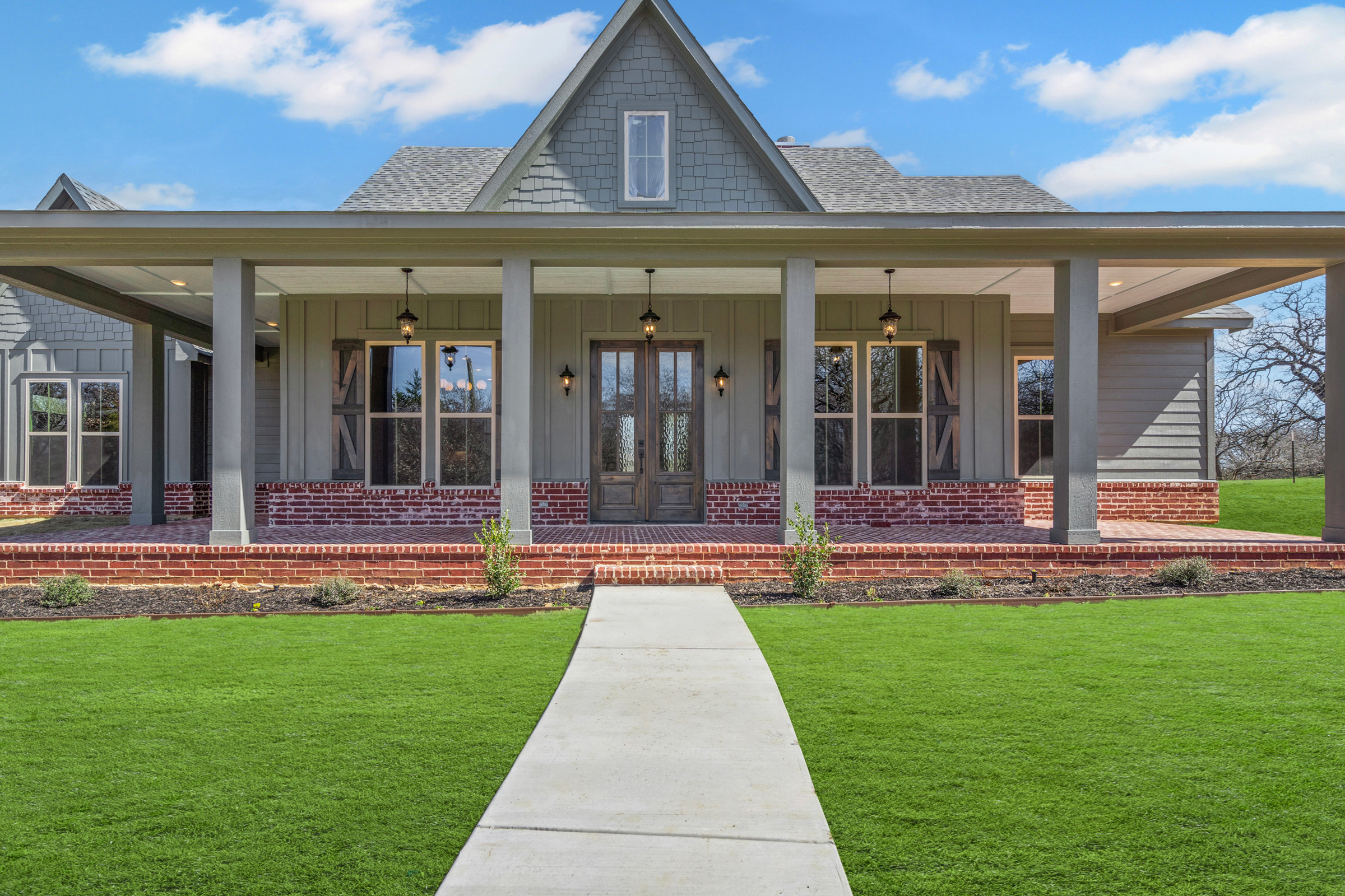 Front view of modern farmhouse with green lawn