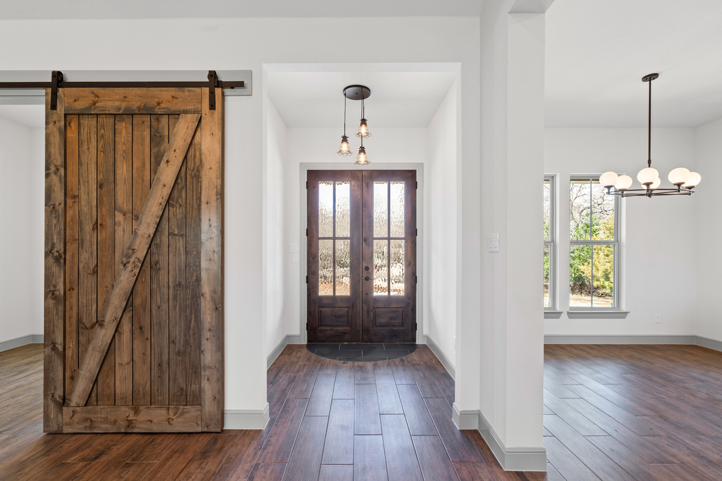 Modern farmhouse interior with wooden doors and lighting.