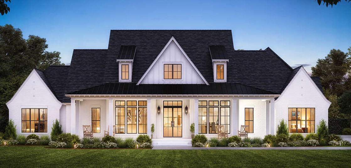 Modern farmhouse with large windows and porch at dusk.