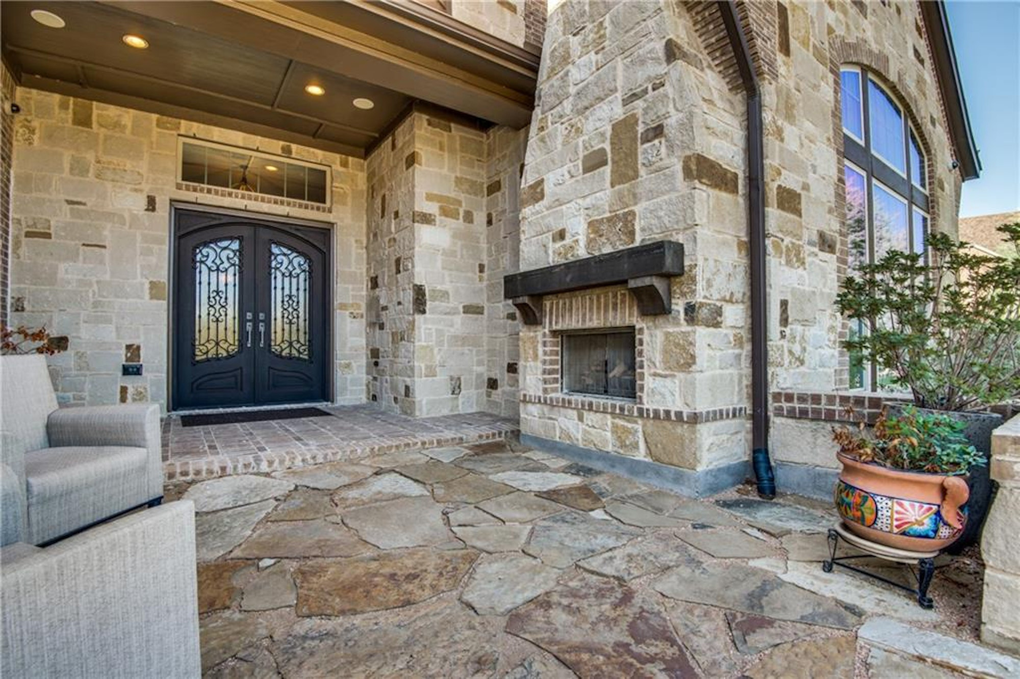 Stone patio with elegant double doors and fireplace.